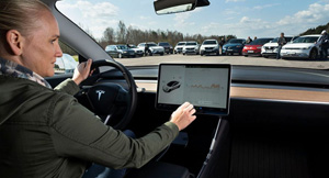 A blonde woman uses the touch screen centre console in a Tesla model 3