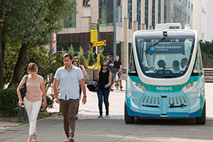 A self-driving pod shares the pavement with some pedestrians headed for La Defence in Paris.