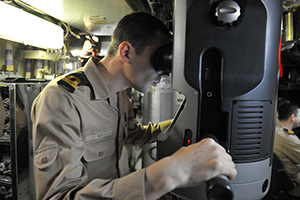 A naval officer inspects a submarine's surrounding using a modern periscope device.